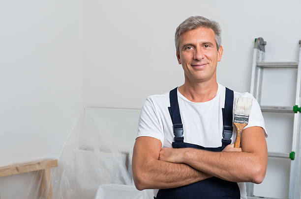 Man painting a wooden house with black paint